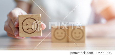Hand choosing unhappy angry face from Emotion block. customer review, bad experience, negative feedback, satisfaction, survey, rating service, assessment, mood, world mental health day concept Hand choosing unhappy angry face from Emotion block. customer review, bad experience, negative feedback, satisfaction, survey, rating service, assessment, mood, world mental health day concept 95580859