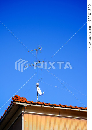 A TV antenna installed on the roof of a detached house that can also watch satellite broadcasts 95581860