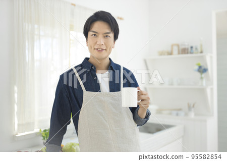 A man in an apron standing in the kitchen A man in an apron standing in the kitchen 95582854