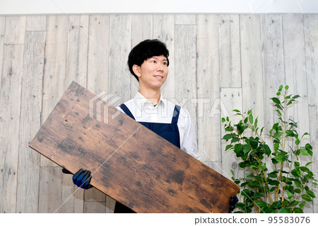 A man in an apron with DIY wood 95583076