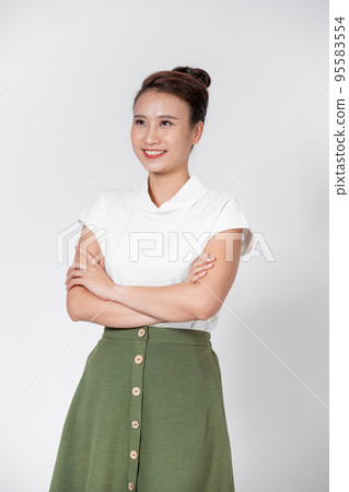 Portrait of a young asian woman with a pleasant smile and crossed arms isolated on white wall Portrait of a young asian woman with a pleasant smile and crossed arms isolated on white wall 95583554