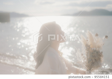 Photo of a woman standing by the beach Photo of a woman standing by the beach 95584151