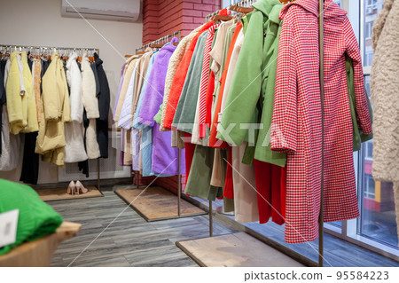 Colorful women's dresses, jackets, trousers and other clothes on hangers in a retail store. The concept of fashion and shopping. Women's clothing boutique. Colorful women's dresses, jackets, trousers and other clothes on hangers in a retail store. The concept of fashion and shopping. Women's clothing boutique. 95584223
