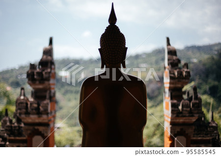 Silhouette of a buddha statue on the background of the balinese gate. Silhouette of a buddha statue on the background of the balinese gate. 95585545
