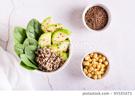 A bowl of quinoa, avocado and spinach on the table. Organic diet. Top view 95585873