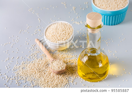 Sesame oil in a glass and seeds in a bowl on the table. Organic Alternative Food Sesame oil in a glass and seeds in a bowl on the table. Organic Alternative Food 95585887
