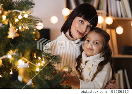 Happy mother and little daughter decorating christmas tree at home. Happy mother and little daughter decorating christmas tree at home. 95586315