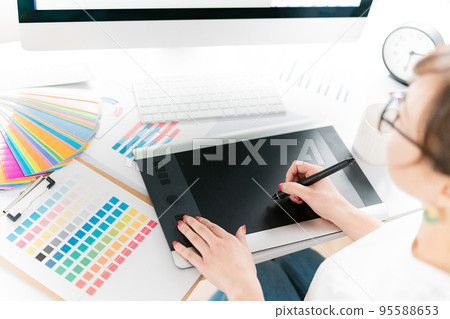 A female graphic designer and illustrator working with a pen tablet A female graphic designer and illustrator working with a pen tablet 95588653