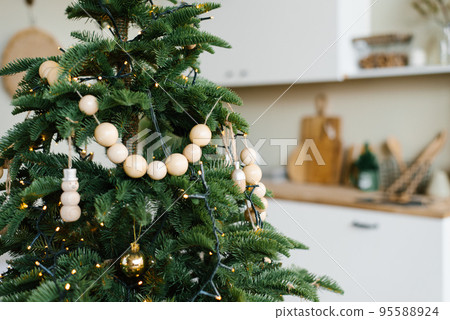 Stylish wooden beads on a Christmas tree in the dining room of a Scandinavian home 95588924