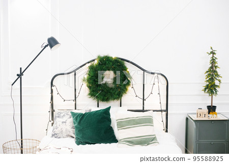 Romantic bedroom in light colors, decorated for New Years and Christmas celebrations. New Year's mood at home. White bedroom and Scandinavian Christmas tree. Romantic bedroom in light colors, decorated for New Years and Christmas celebrations. New Year's mood at home. White bedroom and Scandinavian Christmas tree. 95588925