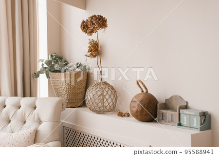 Scandinavian decor as a decoration in the house. Dried hydrangea flowers in a vase, eucalyptus branches in a wicker basket on a shelf in the living room or bedroom 95588941