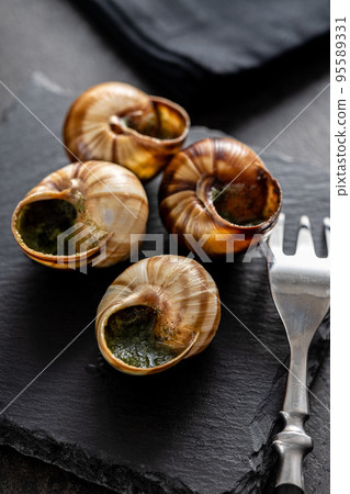 Snails with parsley butter, Bourgogne Escargot Snails on cutting board. Delikatese food. Snails with parsley butter, Bourgogne Escargot Snails on cutting board. Delikatese food. 95589331