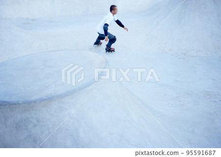 Mature male inline roller training in public skate park. Practicing jumps, tricks. Concept of active lifestyle, sport, hobbies. 95591687