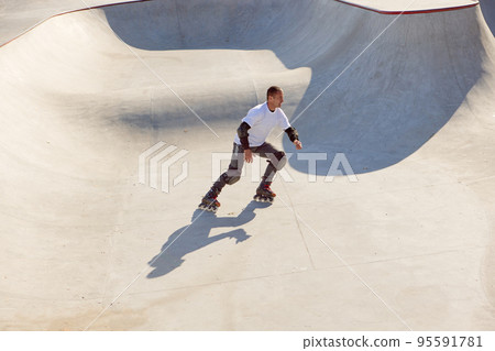 One man, male roller skater on rollerblades training at modern skate park, outdoors. Action, motion, skills and challenges. Doing different tricks One man, male roller skater on rollerblades training at modern skate park, outdoors. Action, motion, skills and challenges. Doing different tricks 95591781