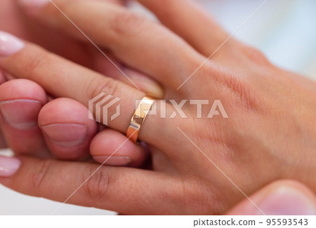mans hand putting a wedding ring on the brides finger. mans hand putting a wedding ring on the brides finger. 95593543