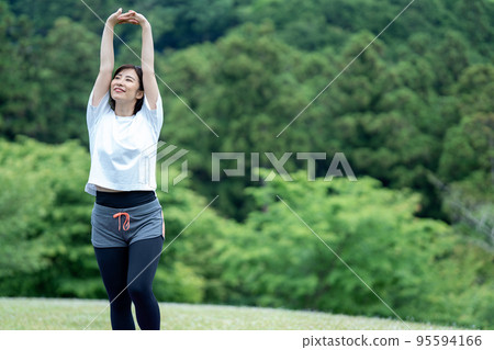 Young woman stretching in the fresh green 95594166