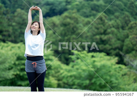 Young woman stretching in the fresh green 95594167
