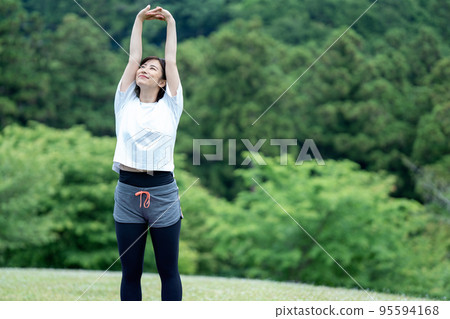 Young woman stretching in the fresh green Young woman stretching in the fresh green 95594168