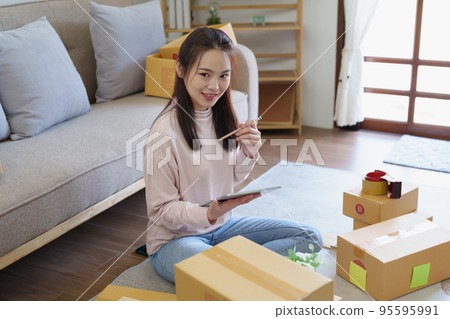 Portrait of Starting small businesses, Asian woman check online orders Selling products working with boxs freelance work at home office, sme business concepts 95595991