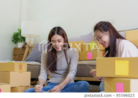 Portrait of Starting small businesses, two Asian woman check online orders Selling products working with boxs freelance work at home office, sme business concepts Portrait of Starting small businesses, two Asian woman check online orders Selling products working with boxs freelance work at home office, sme business concepts 95596025
