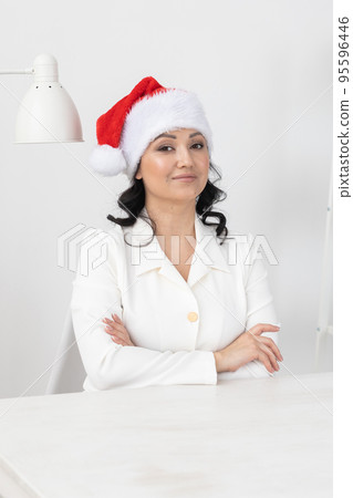 Successful young woman wears christmas santa hat on background beauty office. Portrait professional beautician and winter holidays 95596446