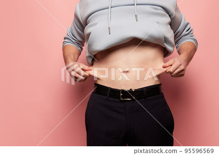 Cropped image of man showing his belly, abdomen. Close Up part of man's body. Concept of dieting, sport, fitness, healthy lifestyle, body positive 95596569