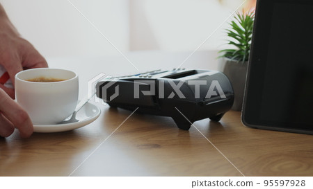 Close up woman makes coffee for a customer who pay using credit card contactless payment spending money in cafe with digital transaction service. 95597928