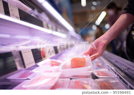 A woman's hand holding a pack of fish fillets A woman's hand holding a pack of fish fillets 95598491