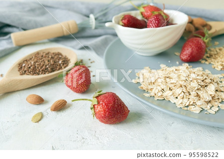 Oatmeal, fresh strawberries on a plate, raisins, nuts and seeds, on the table, healthy breakfast ingredients Oatmeal, fresh strawberries on a plate, raisins, nuts and seeds, on the table, healthy breakfast ingredients 95598522