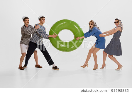 Portrait of two stylish young women pulling big swimming circle with seamen over white background. Portrait of two stylish young women pulling big swimming circle with seamen over white background. 95598885