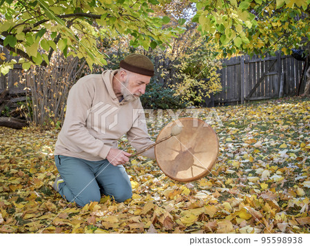 senior man is playing a shaman drum 95598938