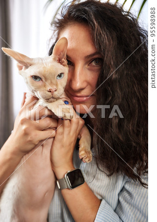Portrait of young woman holding cute cat with blue eyes. Female hugging her cute short hair kitty. Background, copy space, close up. Adorable domestic pet concept. Portrait of young woman holding cute cat with blue eyes. Female hugging her cute short hair kitty. Background, copy space, close up. Adorable domestic pet concept. 95598988