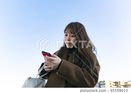 看一個紅色智能手機的婦女 看一個紅色智能手機的婦女 95599013