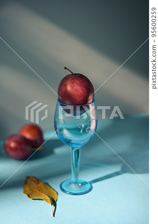 Abstract Ripe plums in small glass 95600259