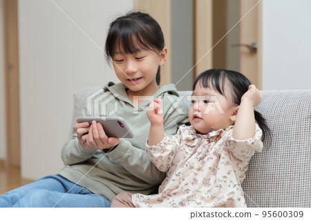 Sister girls playing with smartphones Sister girls playing with smartphones 95600309