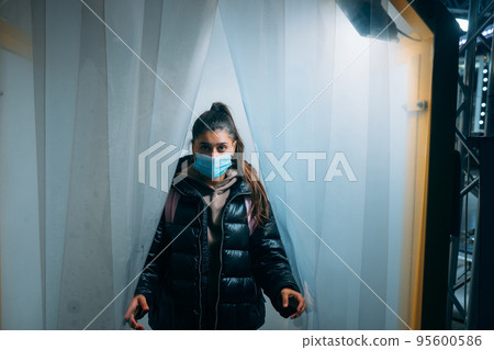 Woman at medic mask is staying in a disinfection tunnel 95600586
