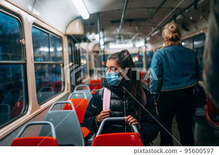 Young woman with mask traveling in the public transport. 95600597