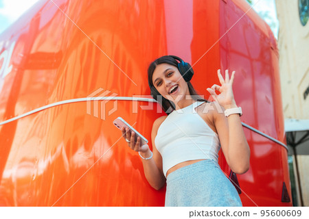 Young woman listening music with wireless headphones in the street Young woman listening music with wireless headphones in the street 95600609