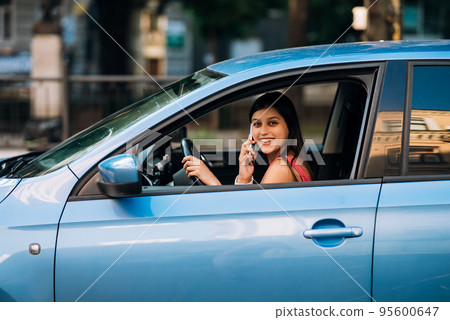 Woman sitting in car and using her smartphone. Woman sitting in car and using her smartphone. 95600647