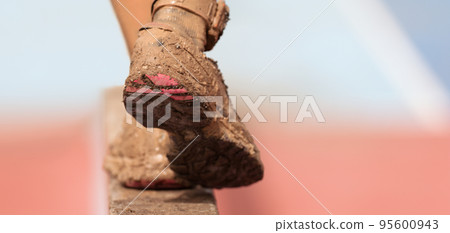 Mud race runners. Participant walking on the obstacle, catches balance Mud race runners. Participant walking on the obstacle, catches balance 95600943