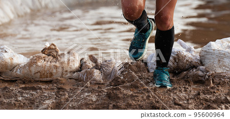 Participant in an obstacle course race runs out of a water obstacle, concept of hardness and effort Participant in an obstacle course race runs out of a water obstacle, concept of hardness and effort 95600964