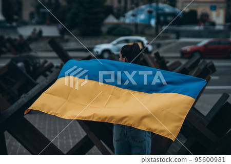 Young woman covered with the Ukrainian flag Young woman covered with the Ukrainian flag 95600981