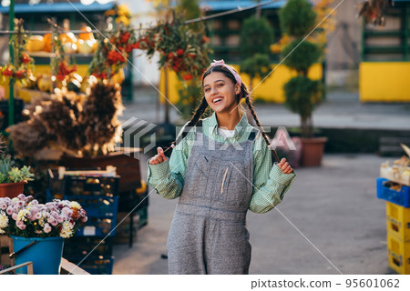 Playful farmer woman in denim overalls smiling sincerely while posing. 95601062