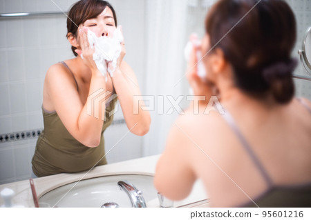 Portrait of a woman washing her face in front of a mirror Portrait of a woman washing her face in front of a mirror 95601216