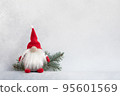 Christmas gnome in red hat with fir branch holiday card on light winter background 95601569