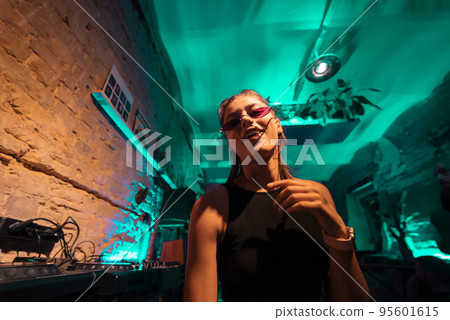 Beautiful female DJ dancing to techno in a small club 95601615