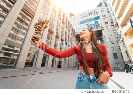 Young female blogger with smartphone streaming on the street. 95601642