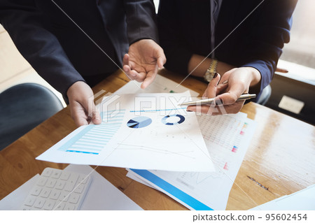 An auditor holds a pen pointing to documents to examine budgets and financial fraud An auditor holds a pen pointing to documents to examine budgets and financial fraud 95602454