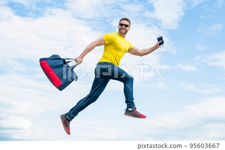 Active guy running with sporty bag midair sky background, sport 95603667