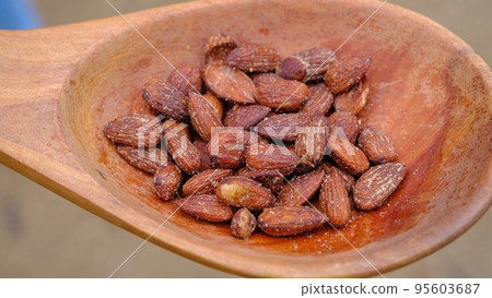 Caramelized almonds with garlic flavor in a wooden spoon 95603687